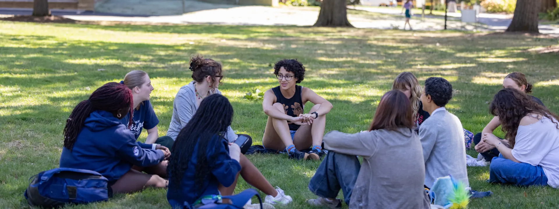 Students sit outside in a circle discussing a reading