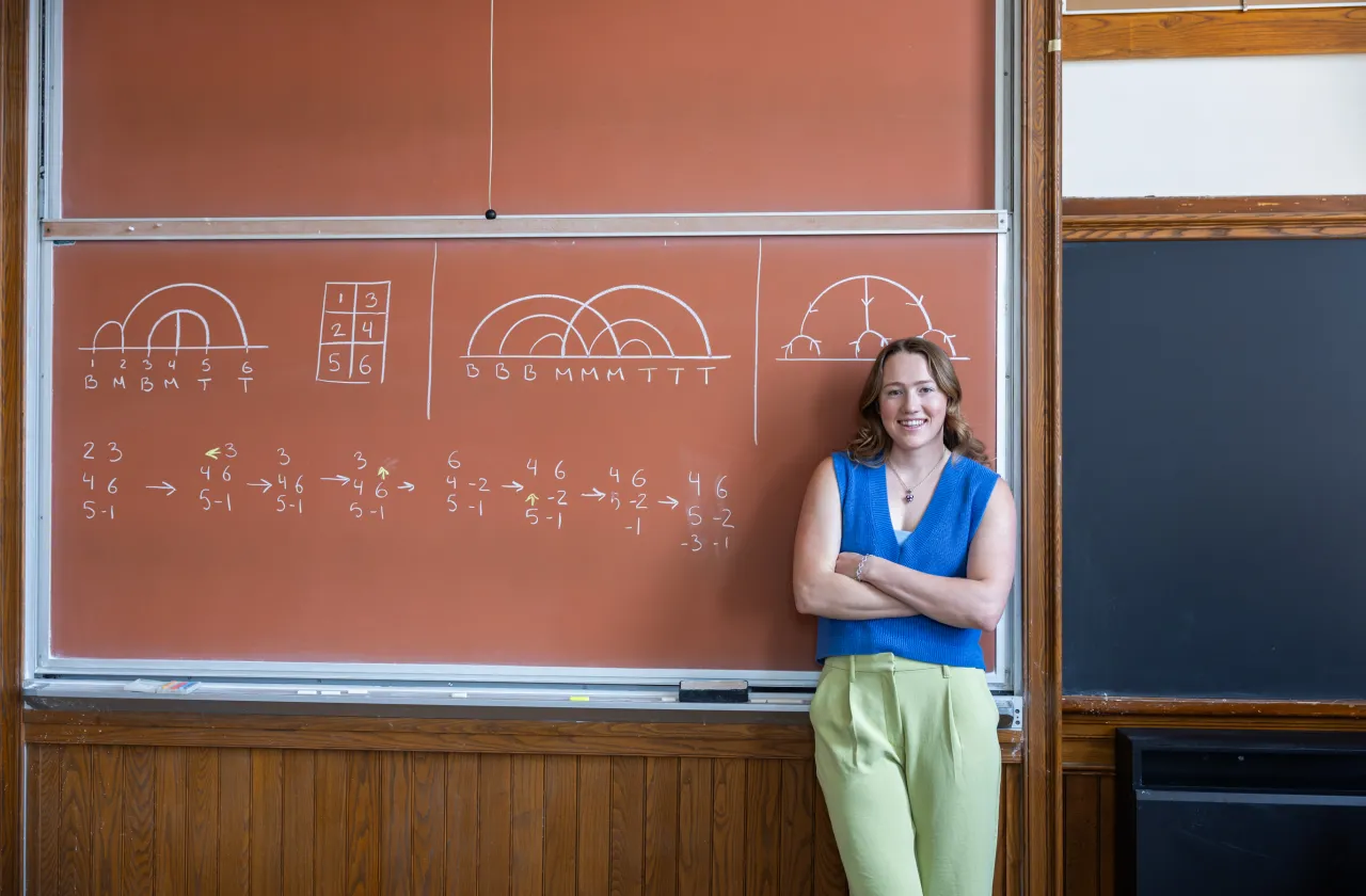 Kerry Seekamp in front of a tan-colored chalkboard.