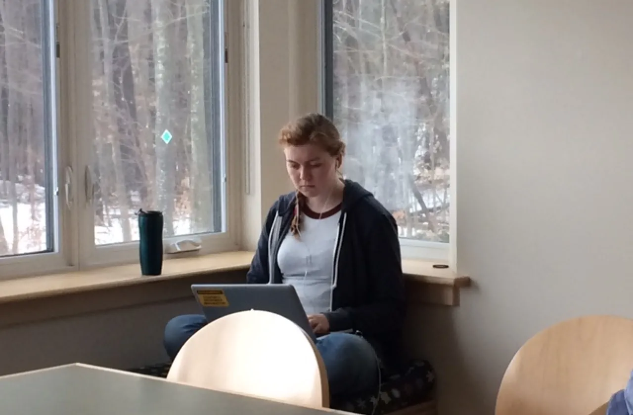 Anna McLane writing on a laptop next to a window