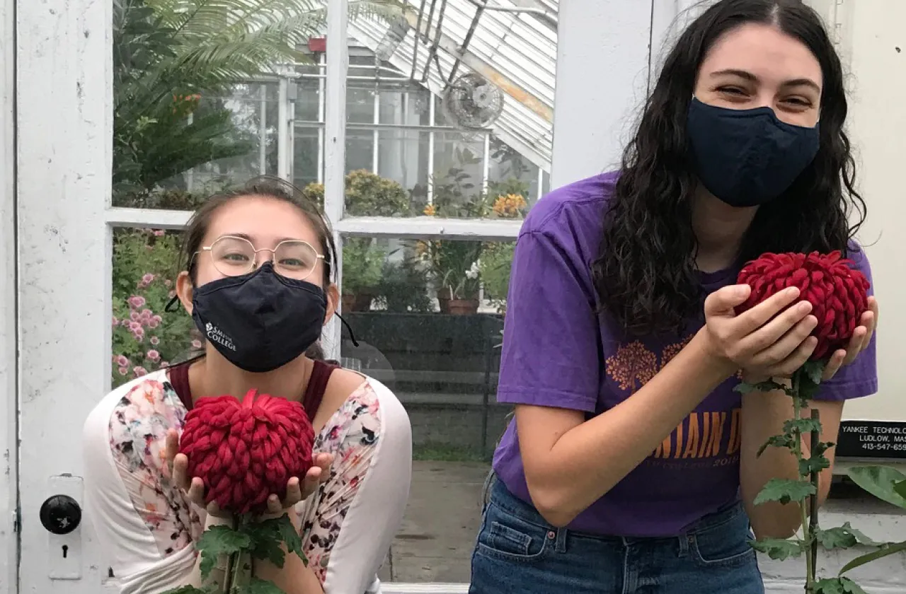 Mai Klooster and Sasha Zeidenberg holding large mum flowers