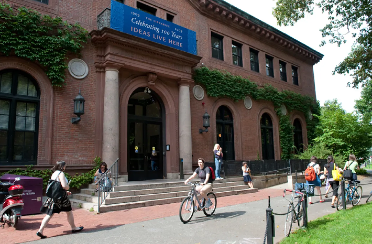 Outside of Neilson library in summer with students walking and riding past