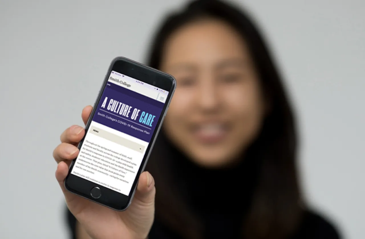 student (blurry) holding a phone (in focus) that shows Smith's Instagram page