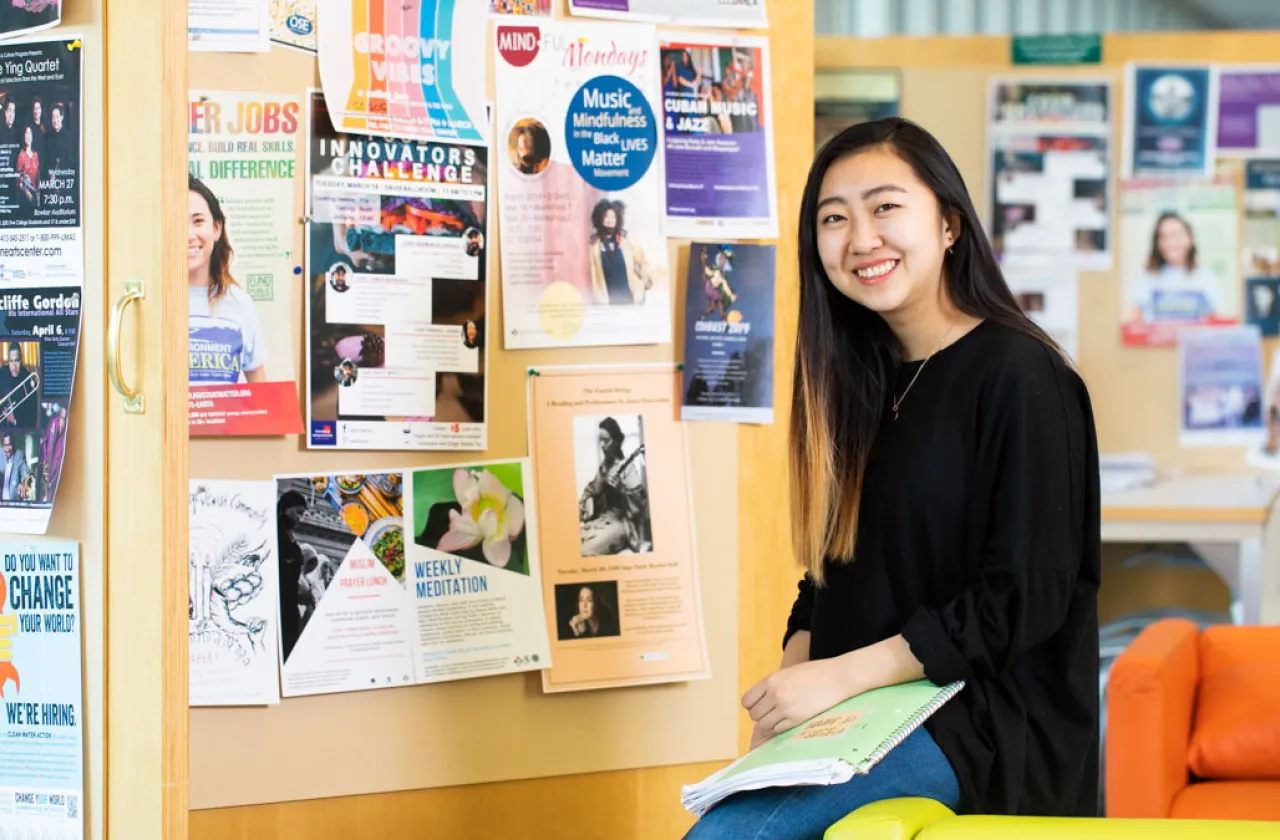 Student in front of a bulletin board covered with posters