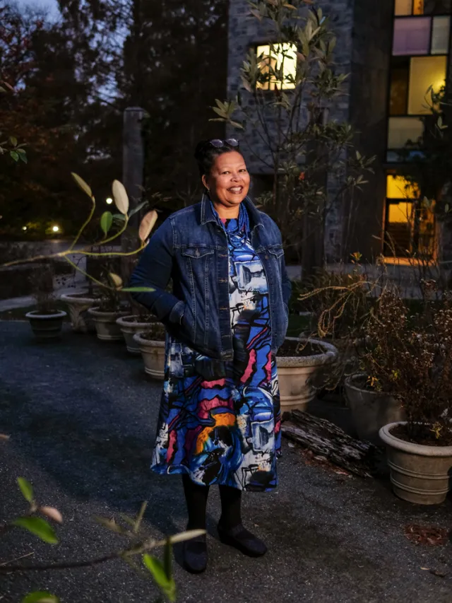 Sarah Willie-LeBreton smiling outside in a garden with her hands in the pockets of a jean jacket