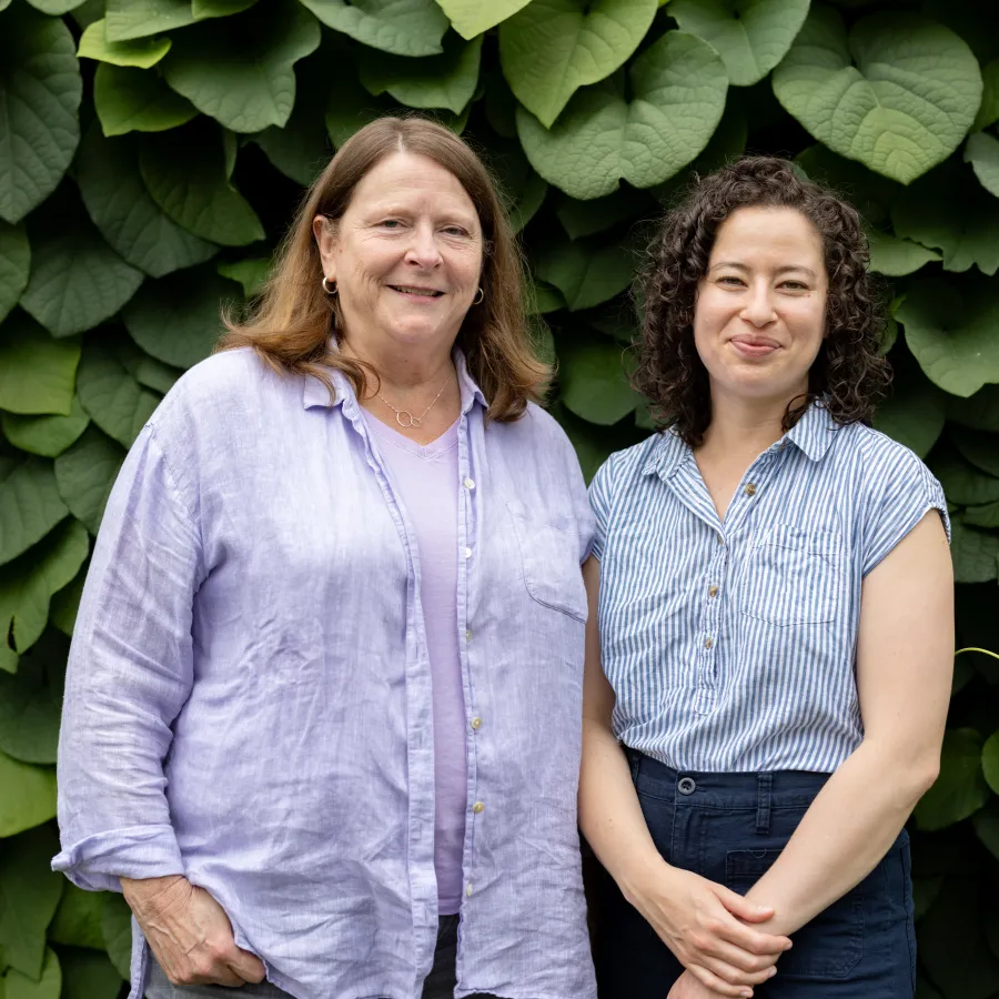 Suzanne Gottschang, the Kahn’s director and professor of anthropology and East Asian studies, and Kathleen Pierce, assistant professor of art, stand in front of dark green leaves