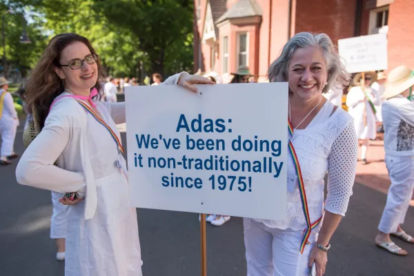 Two alumnae with sign "Adas have been doing it non-traditionally since 1975"