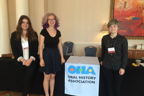 Three students standing by table with OHA logo