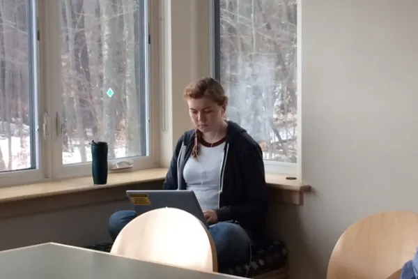 Anna McLane writing on a laptop next to a window