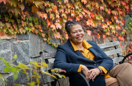 Sarah Willie-LeBreton smiling outdoors and sitting on a bench.
