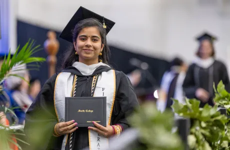 A student holding a diploma at Commencement