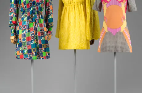 Very short-length dresses on mannequins in a variety of bright colors and patterns.