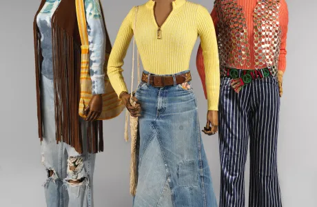Three outfits on mannequins, a variety of jeans or jean skirts with long-sleeved shirts and vests.