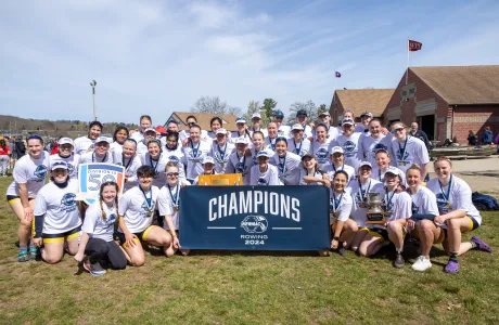 The rowing team posing with their NEWMAC championship banner