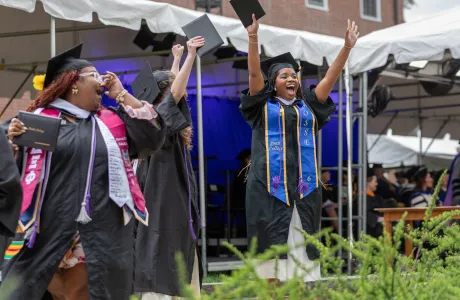 A senior cheers at the crowd after walking across the stage during Commencement