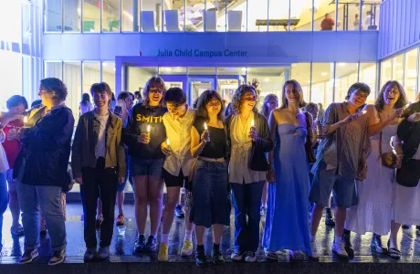A group of seniors hold candles and laugh on the steps outside the Campus Center during Illuminations