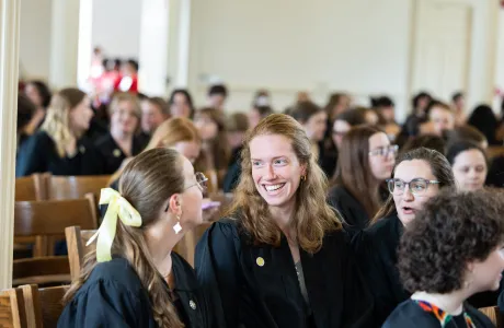 Two seniors laugh in the Chapel during Baccalaureate