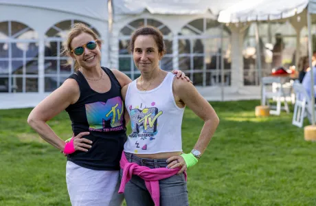 Two alums dressed in MTV t-shirts and sweatbands smile during Reunion