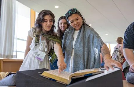 Alums smile and look at a book in Neilson Library during Reunion weekend