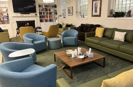 The Bodman lounge in the chapel, featuring a large TV, fireplace, comfortable chairs and sofas, and a large bookshelf.