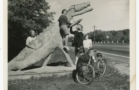 Smith students in 1952 climbing on a statue of a dinosaur.