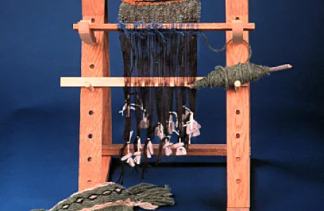 Wooden loom with fabric being woven and yarn hanging