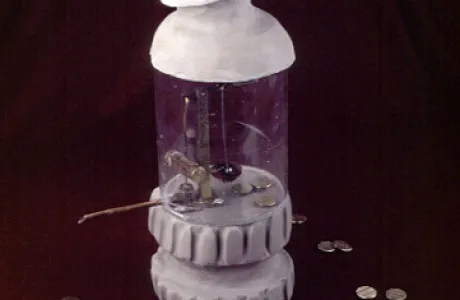 A small sculpture resembling a bottle rocket has a white top, a transparent middle, and coins scattered around its base