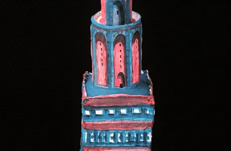 A painted clay sculpture of a tiered tower with blue and red details. A round object tops the tower.