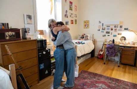 Two students hug in a newly decorated dorm room