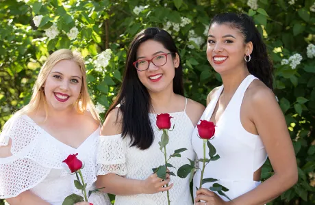 Three students holding red roses on Ivy Day