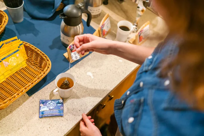 An attendee dunks a "Smithie Breakfast" tea bag in a mug of hot water.