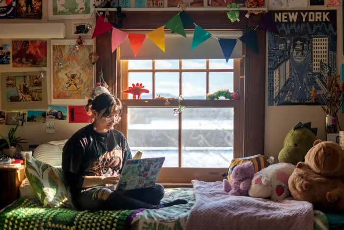 Cloud Osmond sitting on a bed, working on a laptop.