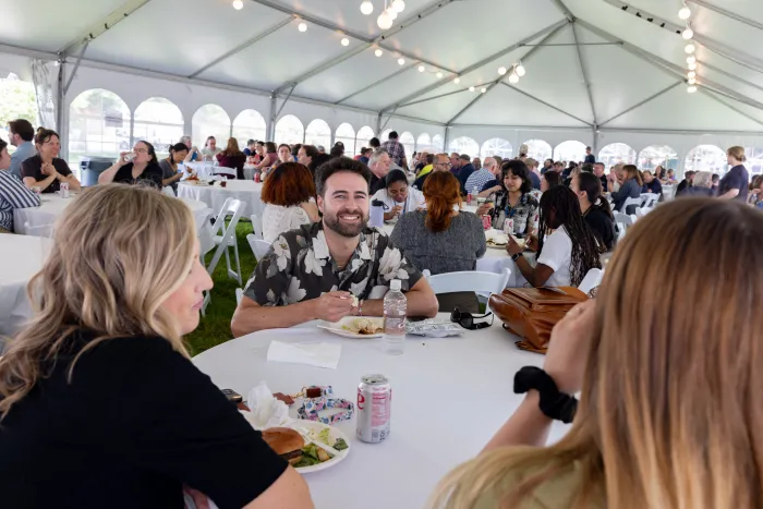 Staff members under a large tent during the staff picnic