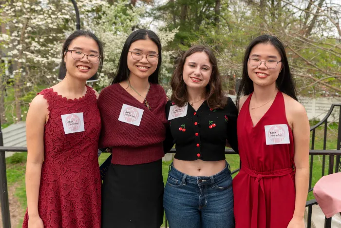 Four students, dressed in red, smile at the camera