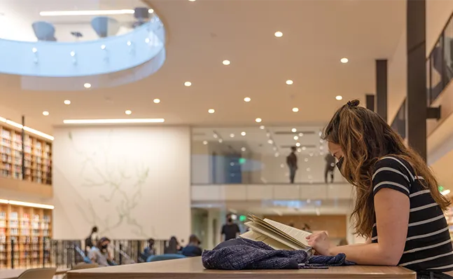 Student sitting at table, reading a book