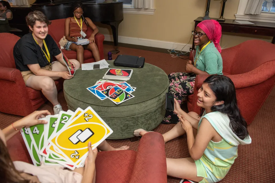 Students sitting in a house living room playing Uno.