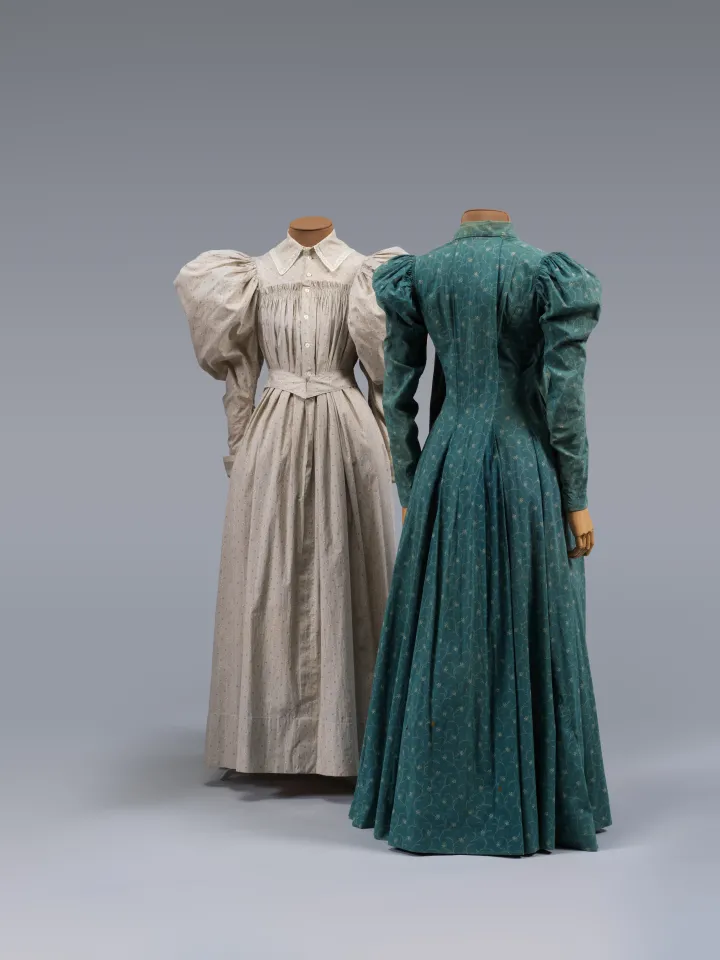 Two floor-length dresses, one grey and one teal, both with large, oversized, puffy long sleeves.