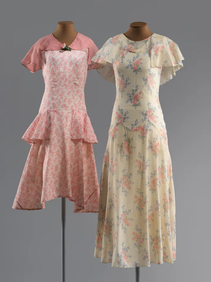Two dresses, one pink and knee-length, the other cream with pink flowers and floor-length, both with frilly short-sleeves.