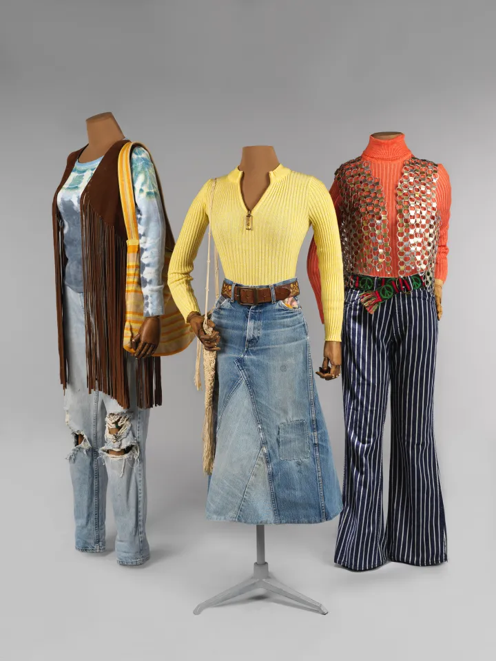 Three outfits on mannequins, a variety of jeans or jean skirts with long-sleeved shirts and vests.