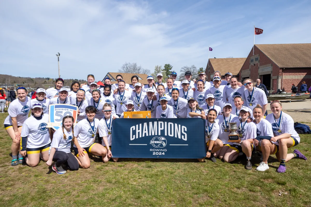 The rowing team posing with their NEWMAC championship banner