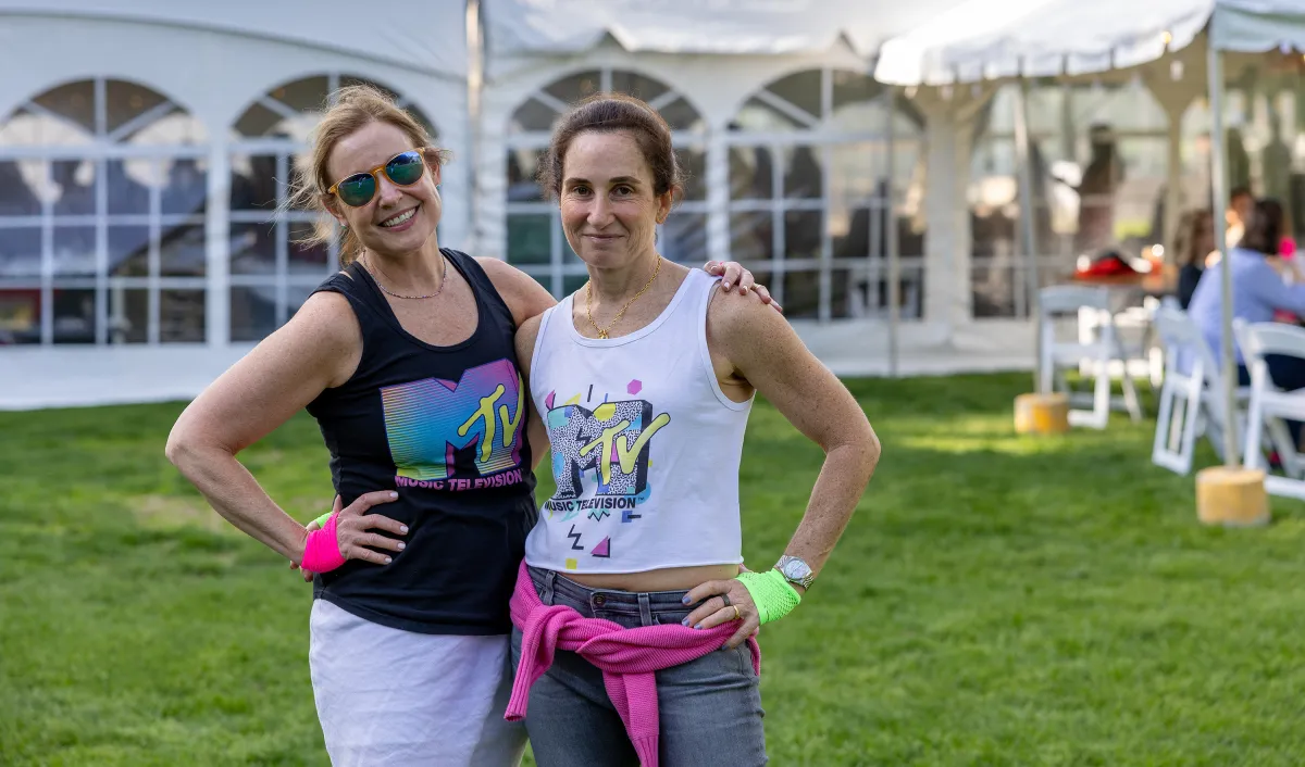 Two alums dressed in MTV t-shirts and sweatbands smile during Reunion