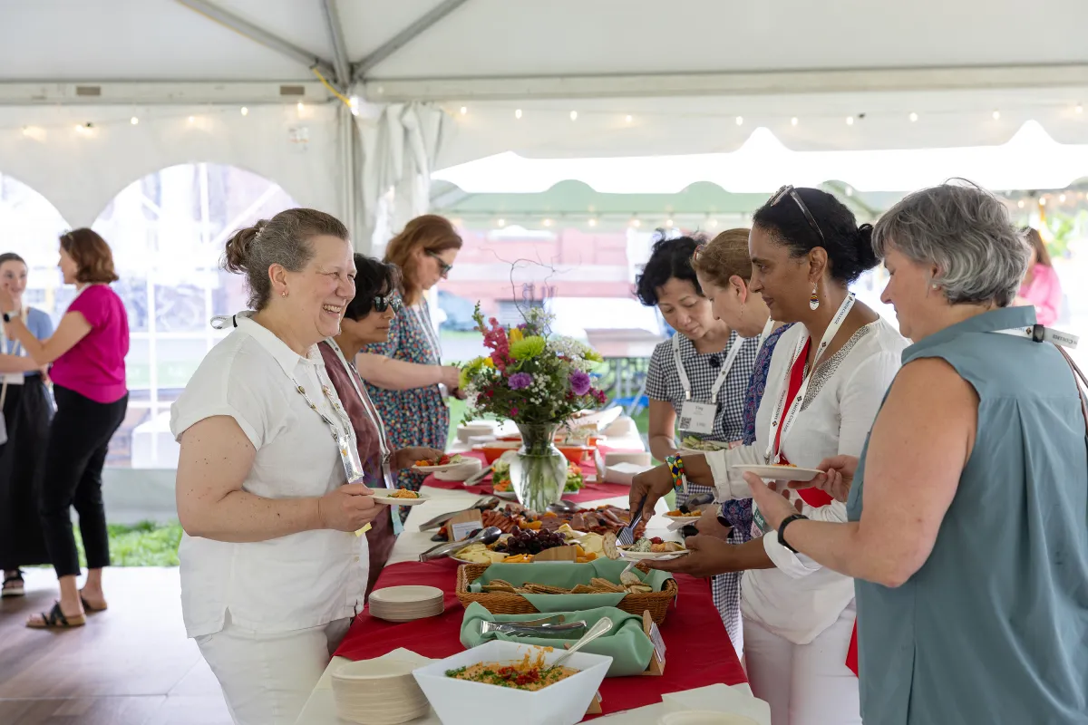 Alums smile and talk over food during Reunion. A beautiful bouquet of flowers adorns the center of the table.