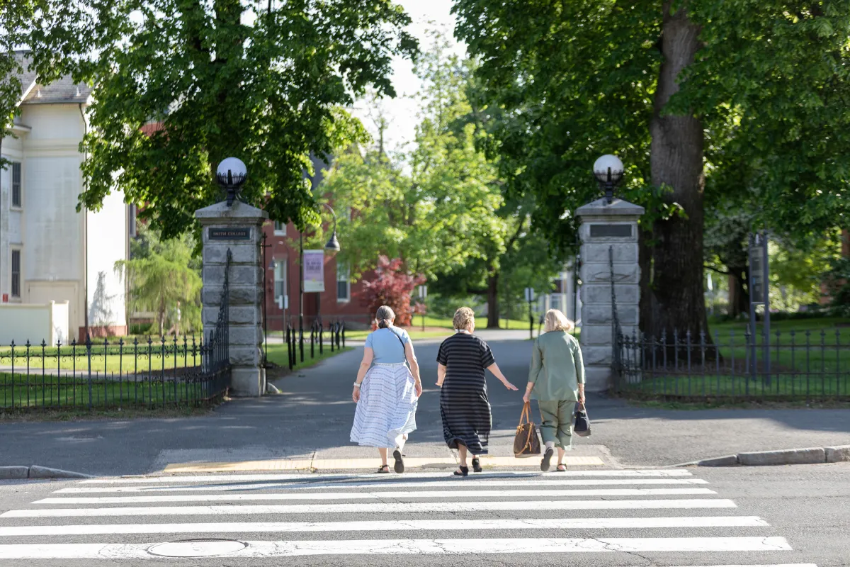 Three alums walking onto campus