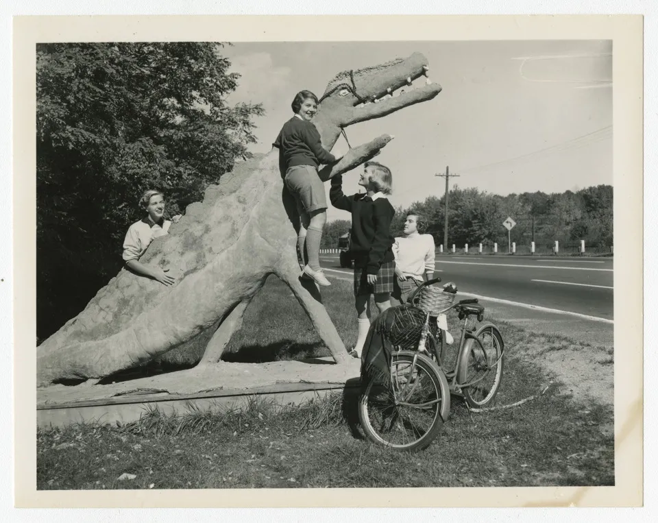 Smith students in 1952 climbing on a statue of a dinosaur.