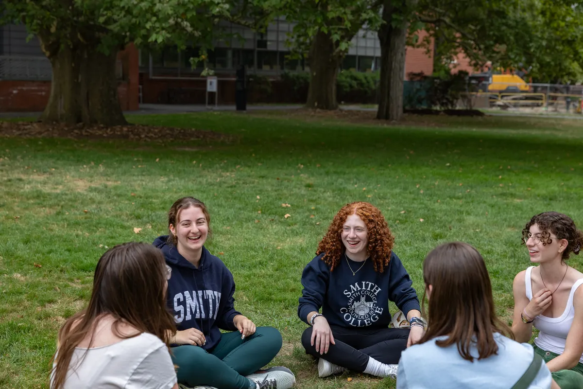 A group of new students sit on the grass and talk