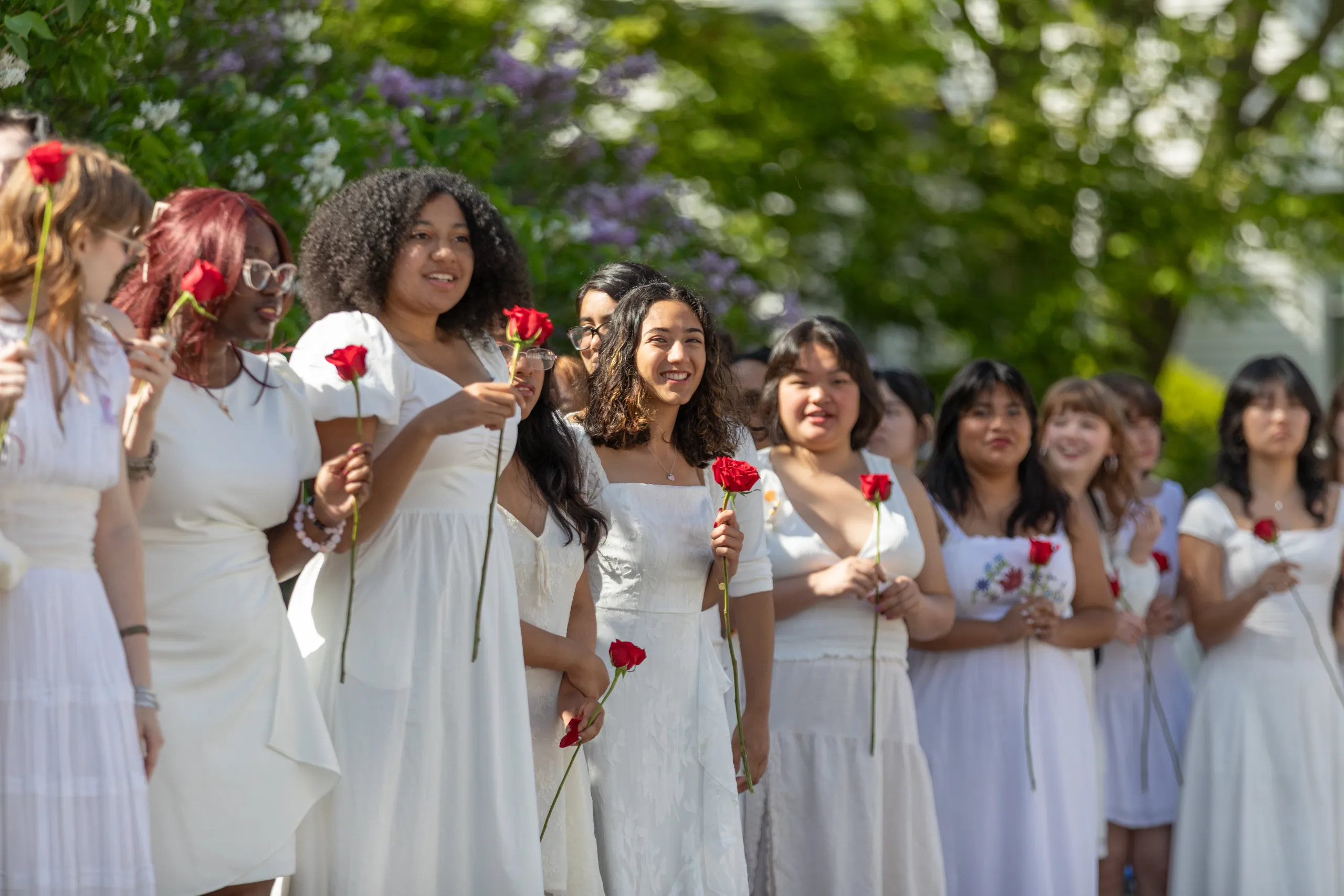 Students wearing white hold roses on Ivy Day