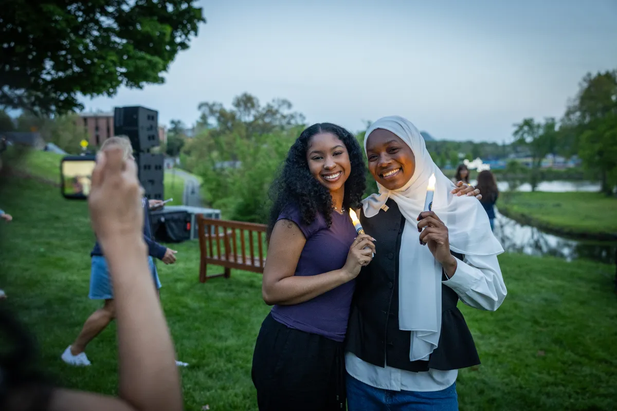 Students pose holding candles during Illumination
