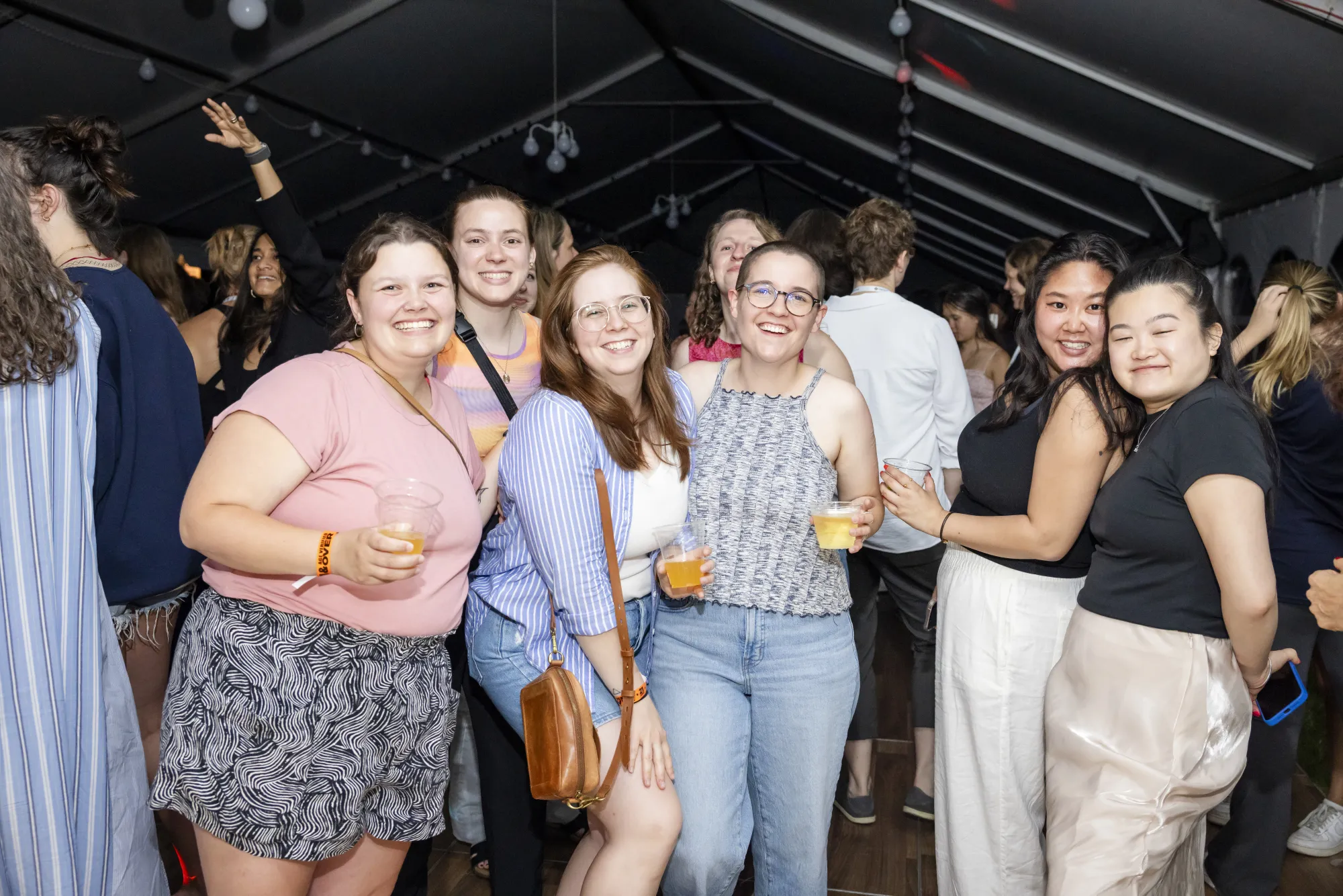 A group of alums smiling at the camera, some holding drinks