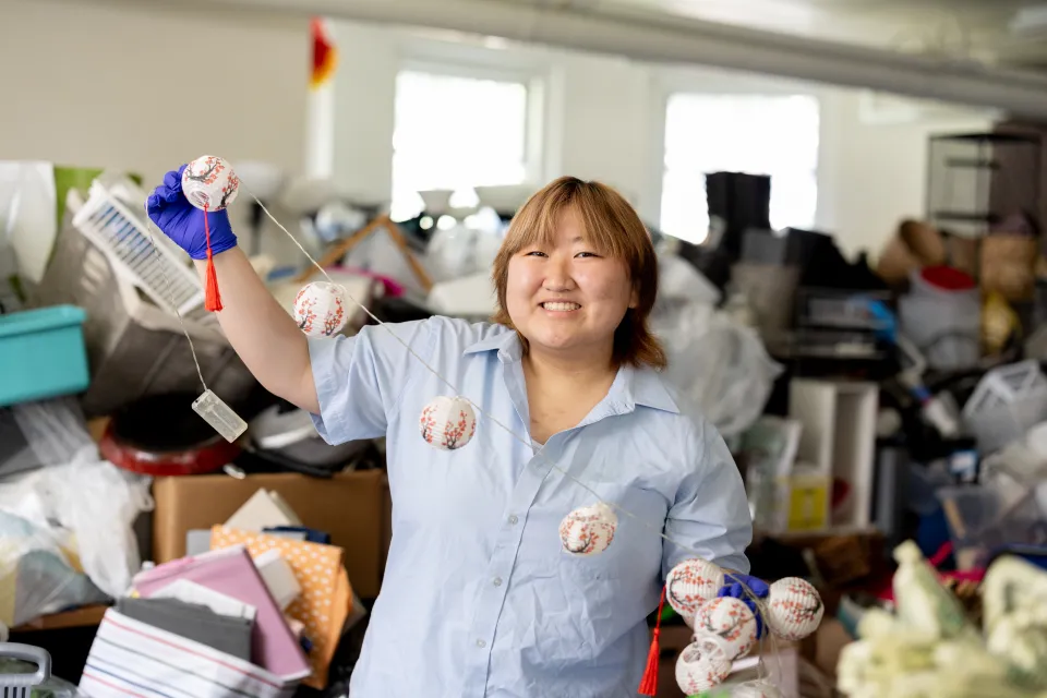 Jena Kim, smiling, holds a string of small paper lantern lights at SmithCycle