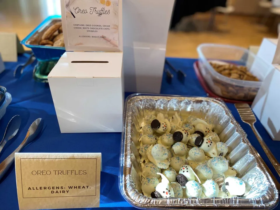 A tray of Oreo truffles (made to look like snowmen) next to a box for voting.