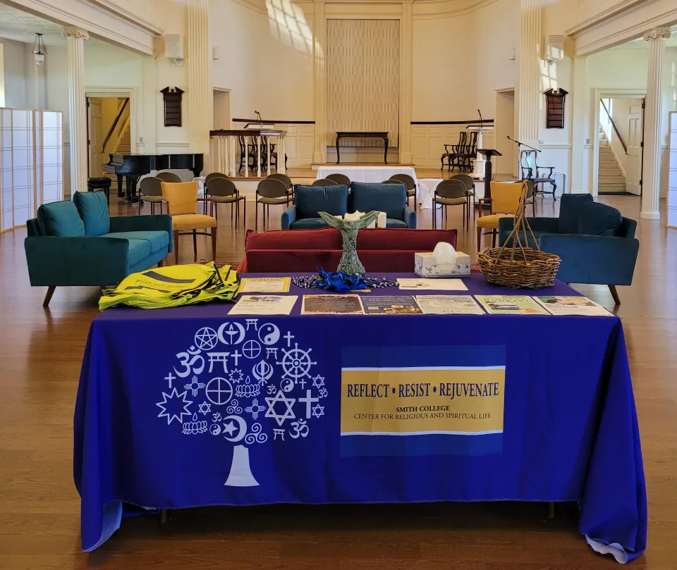 The chapel sanctuary, with a table in front that says "reflect, resist, rejuvenate"